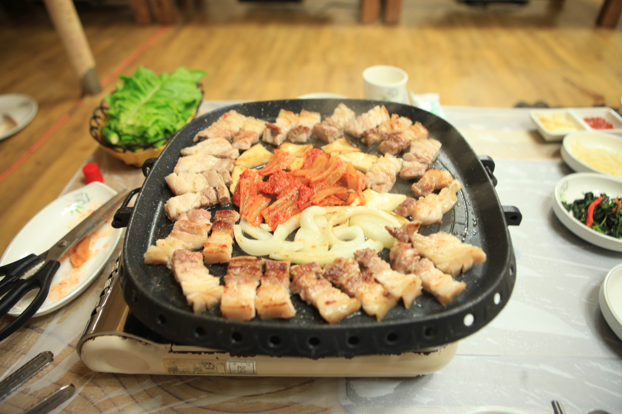 두툼한 삼겹살과 항정살이 불판 위에서 노릇하게 익어가며 김치·양파와 어우러지는 장면.고기의 풍미와 채소의 단맛이 조화를 이루는 ‘진안식 모둠 한 판’으로 여행객들의 사랑을 받고 있습니다.